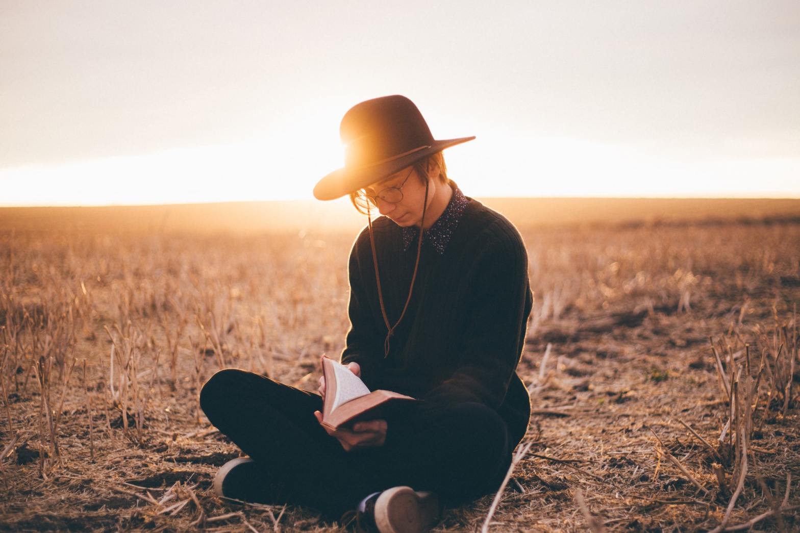 A guy reading in the middle of the field